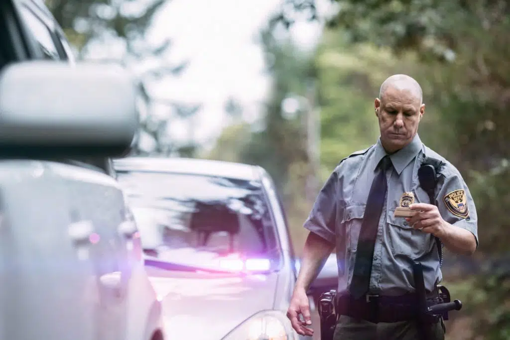 An on duty law enforcement officer, working hard at providing justice, keeping the peace, and making the country a safer place. Here he inspects the drivers license of a person he has pulled over for speeding following checking their information in his patrol car.