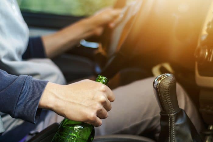 Drinking and driving ,man drinking alcohol and using mobile phone while driving car ,concept drive safely while using a cell phone or drunk alcohol.