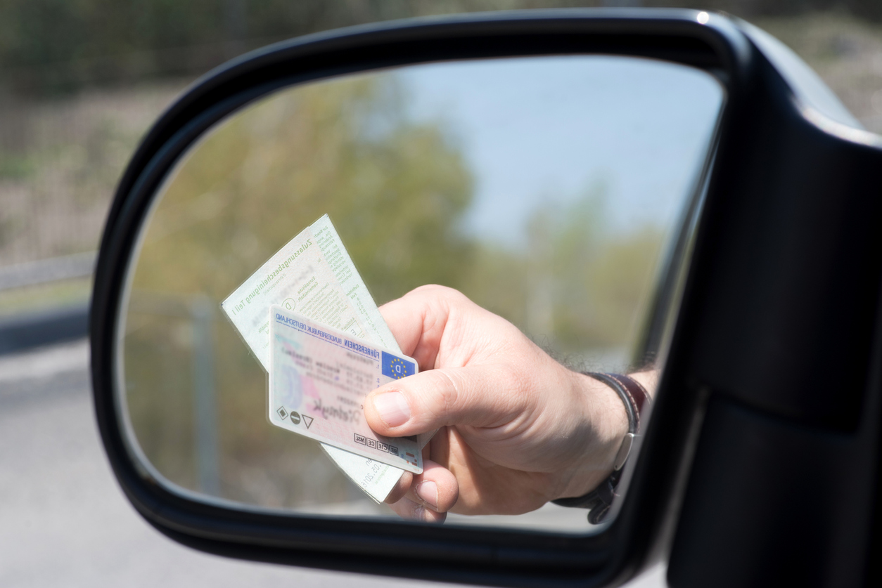 A man shows driver's license and vehicle registration at a check