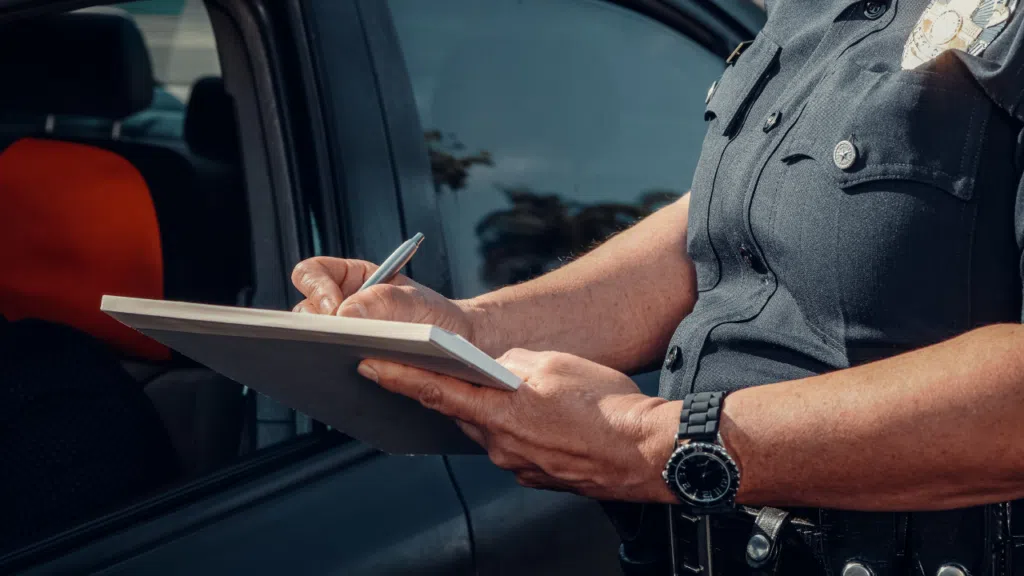 A police officer writing down a traffic ticket to a driver.