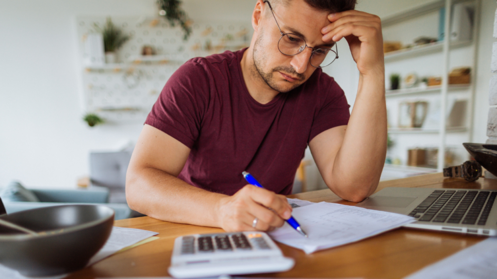 A man paying his bills and looking distressed.